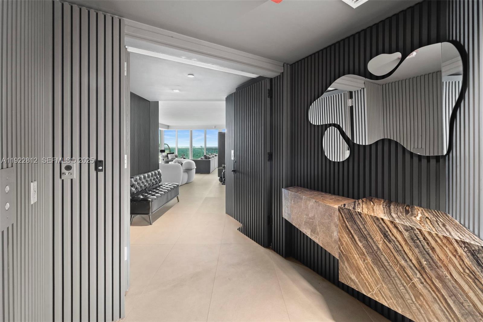 A modern entryway features dark slatted walls, a floating marble console, and an organic-shaped mirror — 2127 Brickell Ave # 3005, Miami FL 33129, MIAMI, FL
