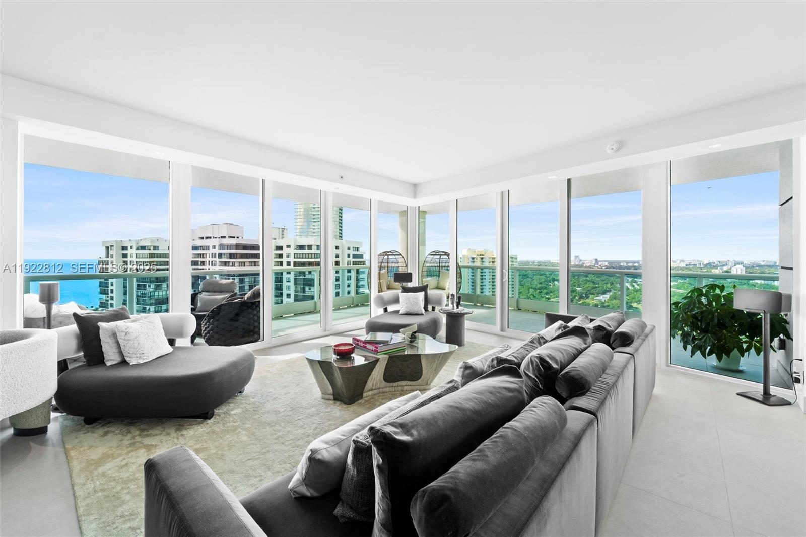 A modern living room features floor-to-ceiling windows with panoramic city and ocean views — 2127 Brickell Ave # 3005, Miami FL 33129, MIAMI, FL