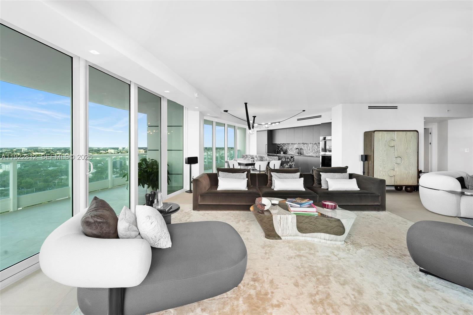 A modern living room features a large sectional sofa, a unique coffee table, and floor-to-ceiling windows — 2127 Brickell Ave # 3005, Miami FL 33129, MIAMI, FL