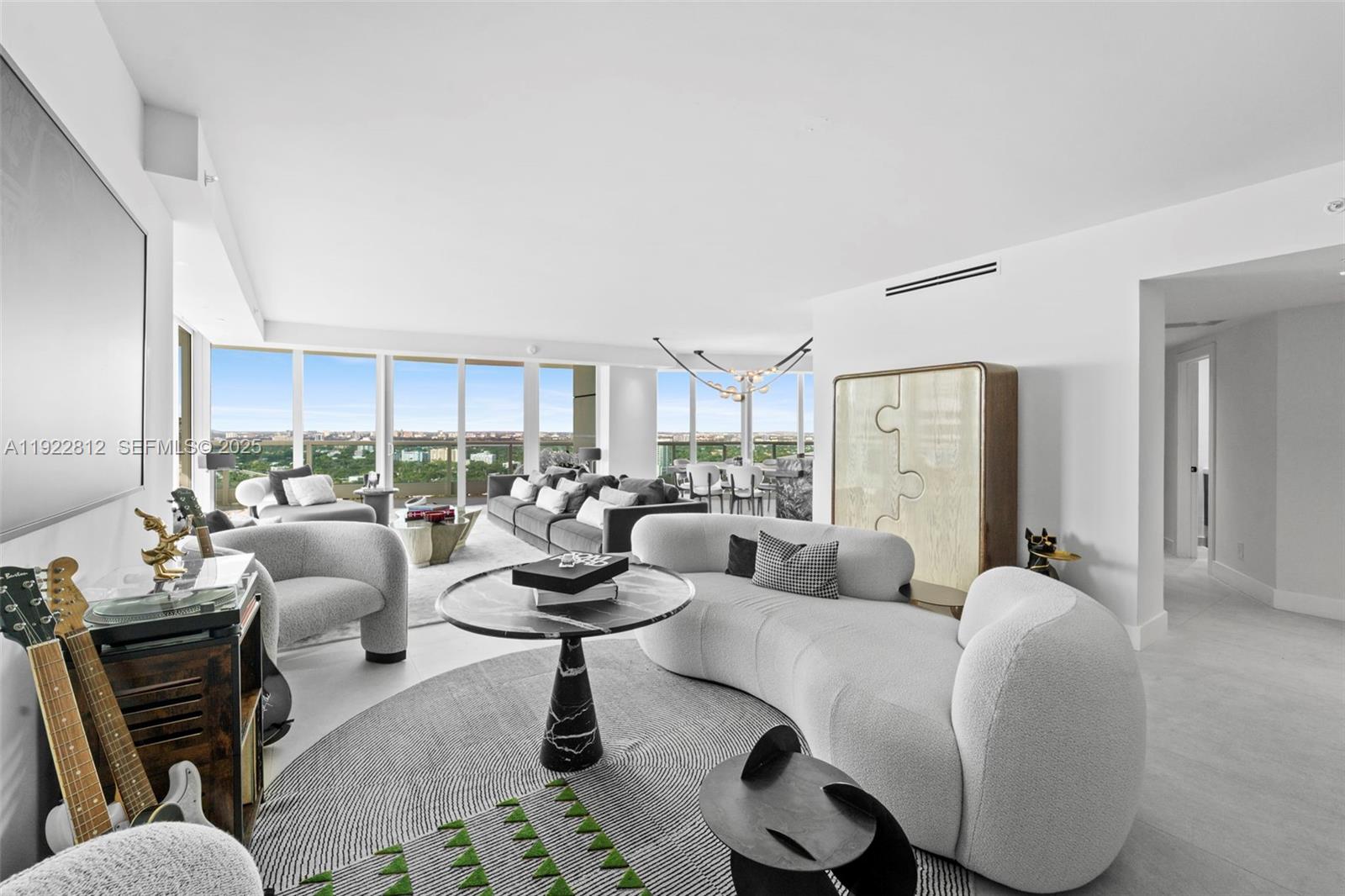 A modern living room features a curved sofa, marble coffee table, and floor-to-ceiling windows — 2127 Brickell Ave # 3005, Miami FL 33129, MIAMI, FL