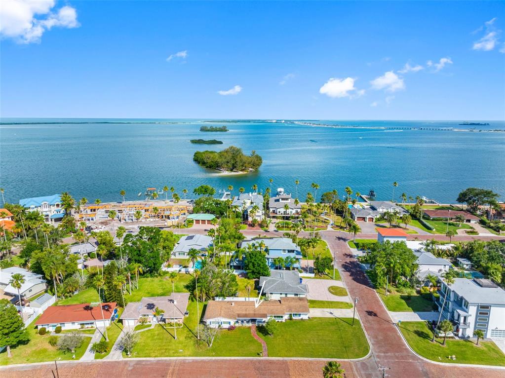 An aerial view shows a single-story house with a brown roof near the waterfront — 1794 SANTA BARBARA DRIVE, DUNEDIN, FL