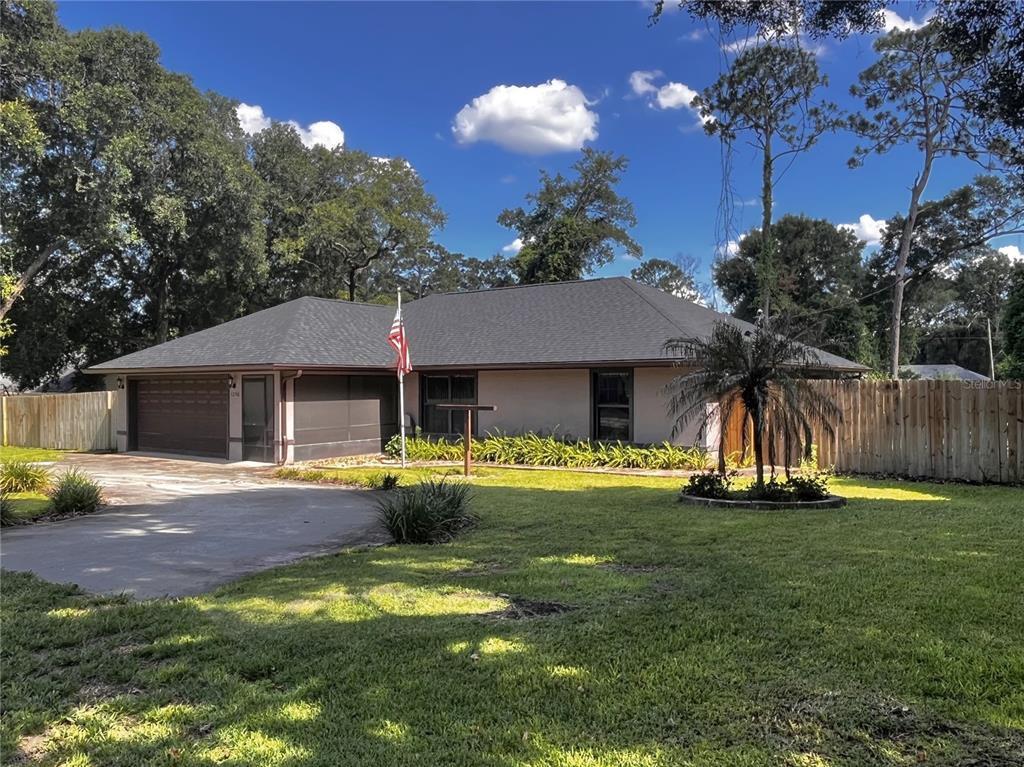 A single-story house with a dark shingled roof, two-car garage, and a front lawn — 1250 15TH STREET, ORANGE CITY, FL