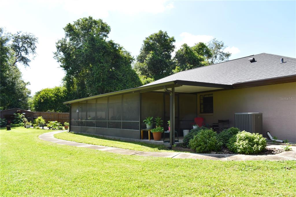 A backyard view shows a house with a screened-in porch and a curved concrete walkway — 1250 15TH STREET, ORANGE CITY, FL