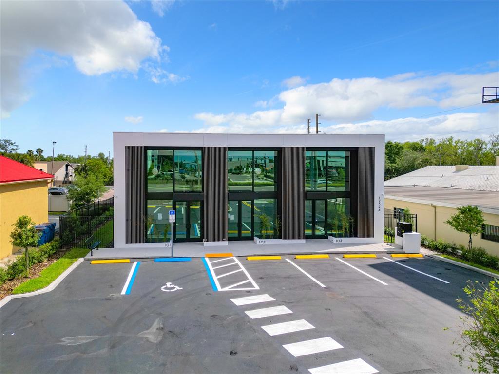 A modern, single-story commercial building with three glass-fronted units and a paved parking lot — 12324 W COLONIAL DRIVE, WINTER GARDEN, FL