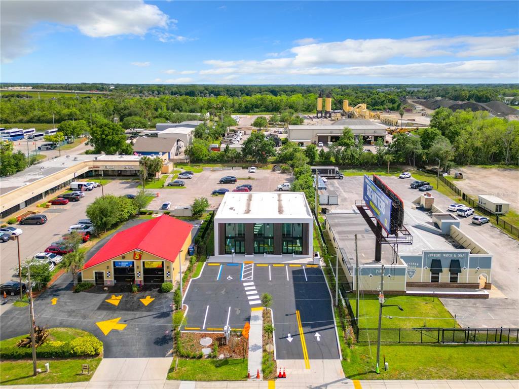 An aerial view shows a modern commercial building with a parking lot and surrounding businesses — 12324 W COLONIAL DRIVE, WINTER GARDEN, FL
