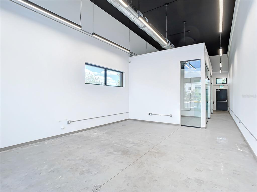 An empty commercial space features white walls, a concrete floor, and an exposed ceiling — 12324 W COLONIAL DRIVE, WINTER GARDEN, FL