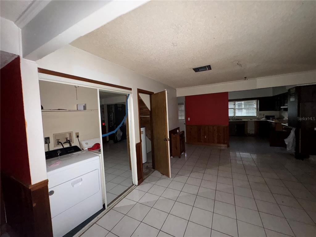 A laundry area with a washer and dryer sits beside a tiled room with wood wainscoting — 11001 SE SUNSET HARBOR ROAD UNIT D21, SUMMERFIELD, FL