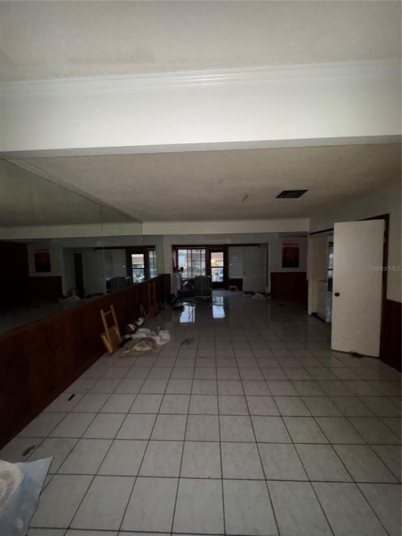 A large room with white tile flooring, wood paneling, and a full-length wall mirror — 11001 SE SUNSET HARBOR ROAD UNIT D21, SUMMERFIELD, FL