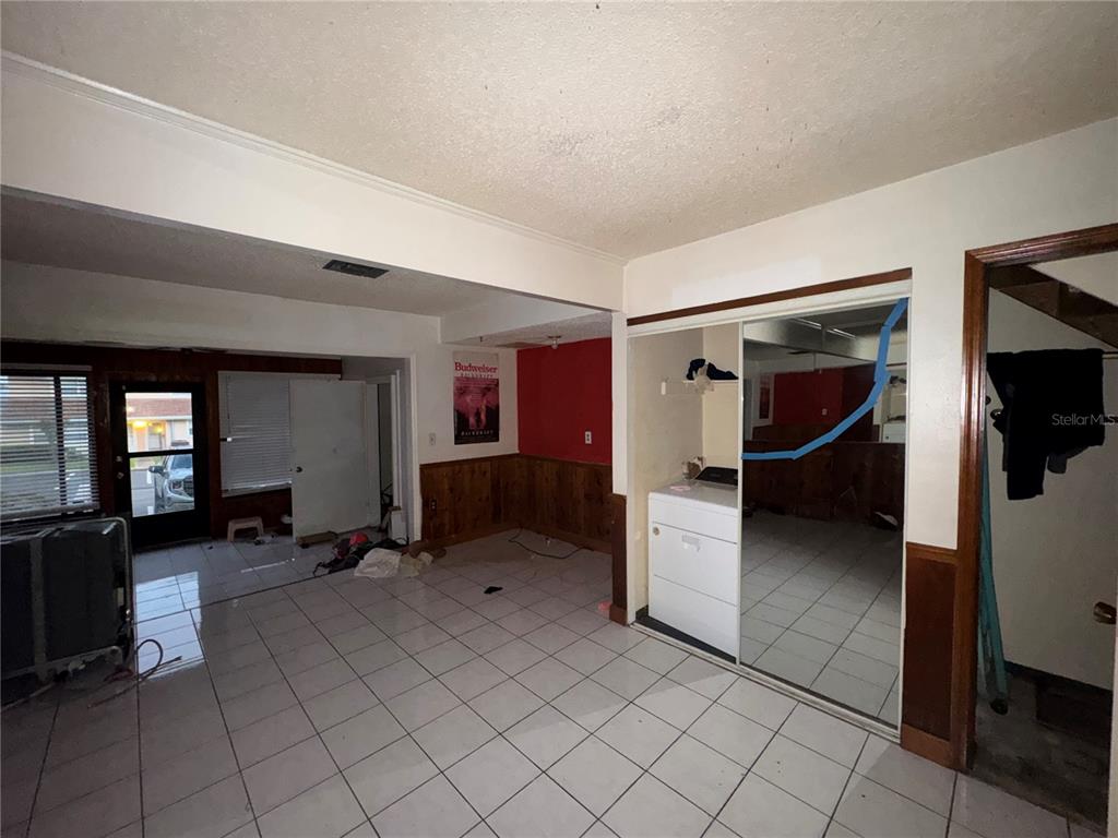 A room with white tile flooring, a red accent wall, and mirrored sliding closet doors — 11001 SE SUNSET HARBOR ROAD UNIT D21, SUMMERFIELD, FL
