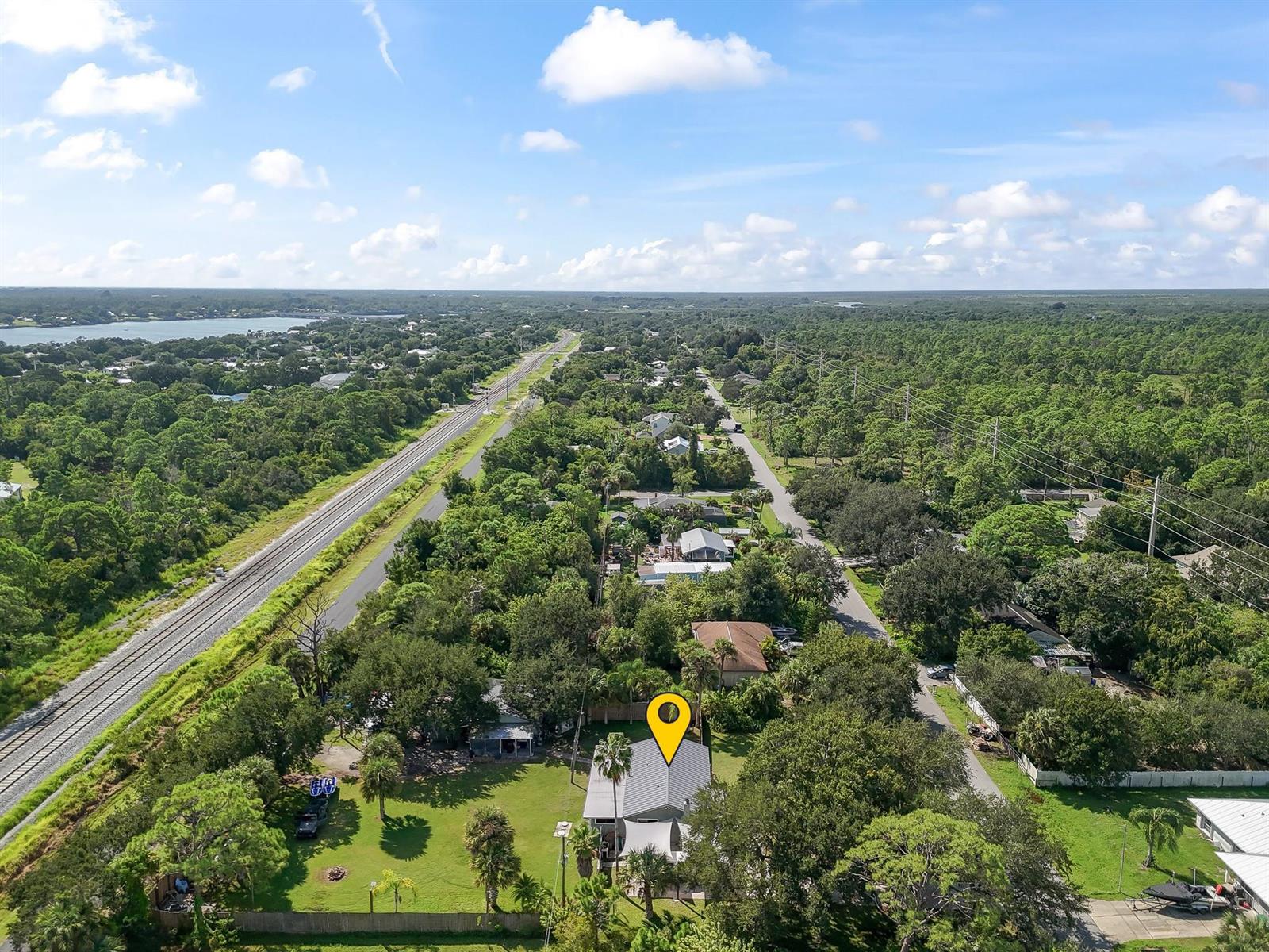 An aerial view shows a house with a metal roof surrounded by trees and greenery — 9633 Honeysuckle, FL 32976, FL
