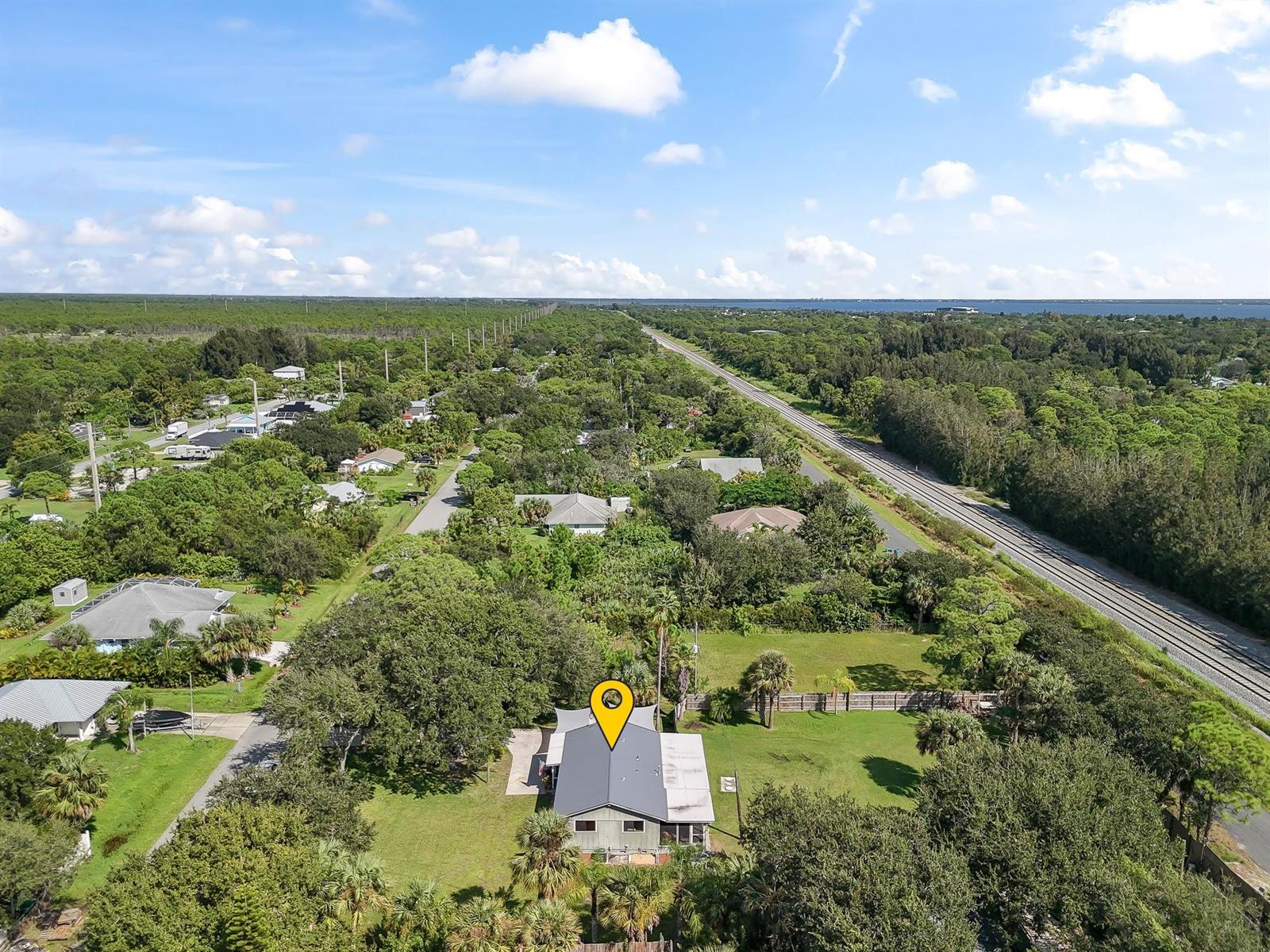 An aerial view shows a house with a gray roof surrounded by trees and grass — 9633 Honeysuckle, FL 32976, FL