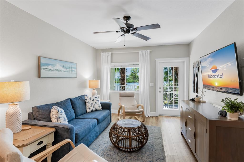 A living room features a blue sofa, a rattan coffee table, and a wall-mounted television — 399 2ND STREET UNIT 215, INDIAN ROCKS BEACH, FL