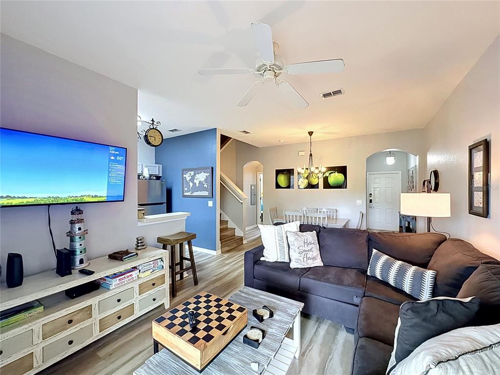 A living room features a sectional sofa, a television, and a dining area beyond — 244 CAPRI DRIVE, DAVENPORT, FL