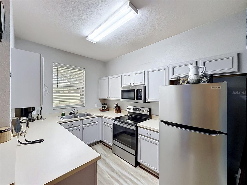 A kitchen features white cabinets, stainless steel appliances, and light-colored countertops — 244 CAPRI DRIVE, DAVENPORT, FL