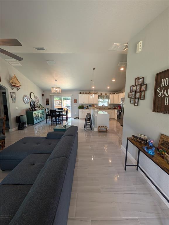 An open-concept living room and kitchen featuring light tile flooring and vaulted ceilings — 5832 NW 63RD PLACE, OCALA, FL