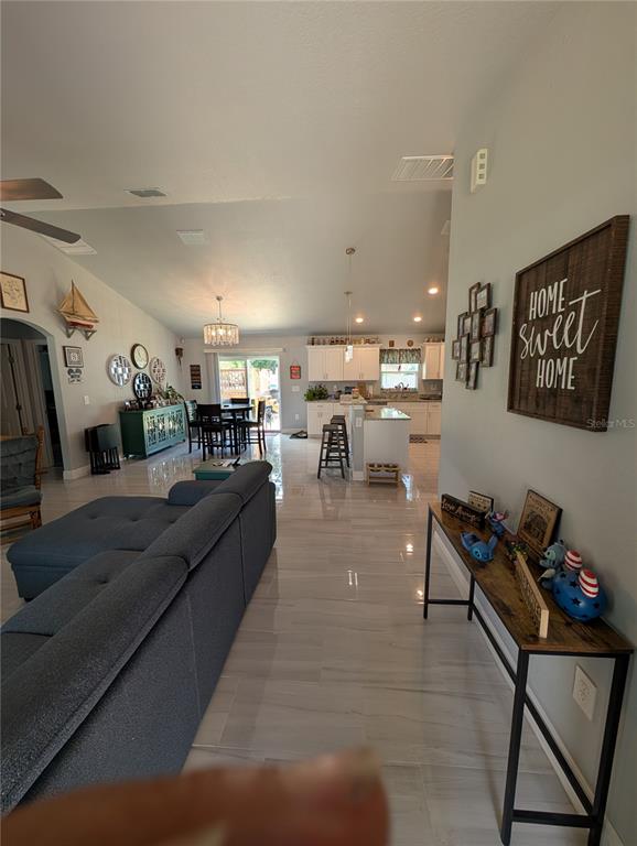 An open-concept living room and kitchen feature light tile flooring and a vaulted ceiling — 5832 NW 63RD PLACE, OCALA, FL