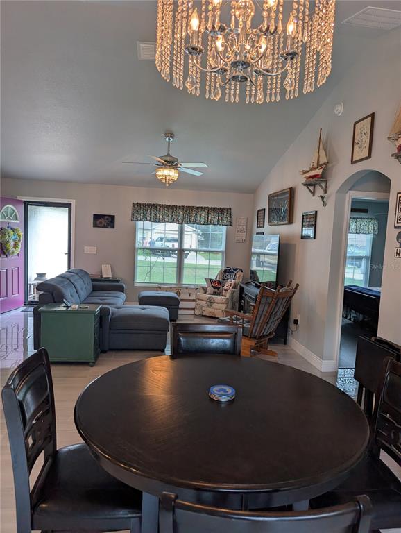 A dining area with a round table opens into a living room with a chandelier — 5832 NW 63RD PLACE, OCALA, FL