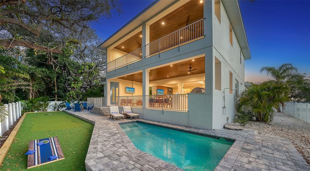 A two-story house features a swimming pool, putting green, and covered balconies at dusk — 1537 SIESTA DRIVE, SARASOTA, FL