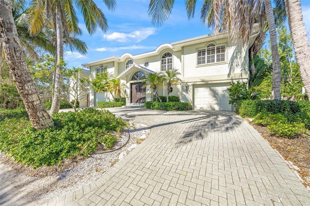 A two-story house with a paved driveway, palm trees, and a two-car garage — 569 JUAN ANASCO DRIVE, LONGBOAT KEY, FL