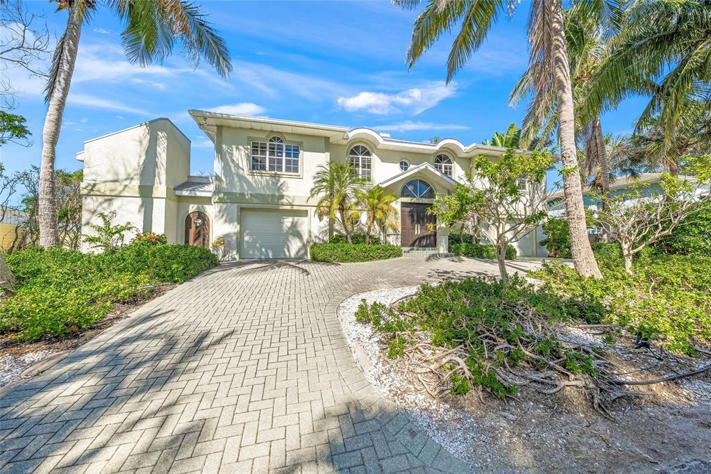 A two-story house with a paved driveway, palm trees, and a multi-car garage — 569 JUAN ANASCO DRIVE, LONGBOAT KEY, FL