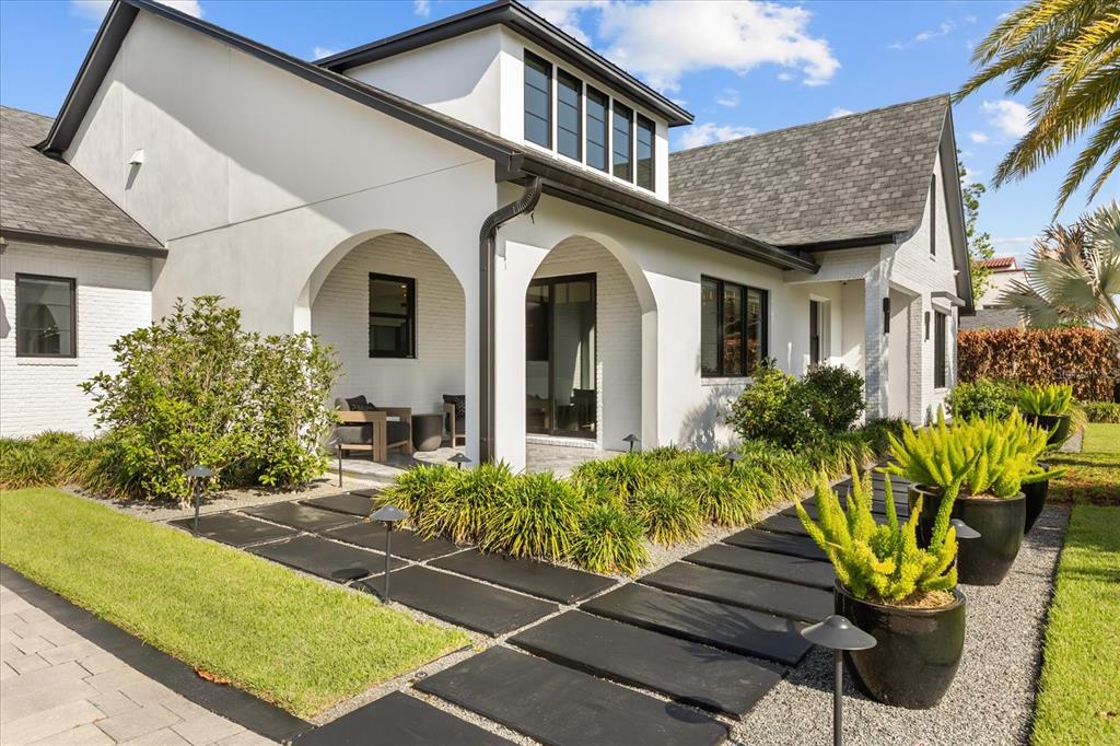 A white house with arched entryways, black window frames, and a modern stone walkway — 1441 CARDINAL COURT, WINTER PARK, FL