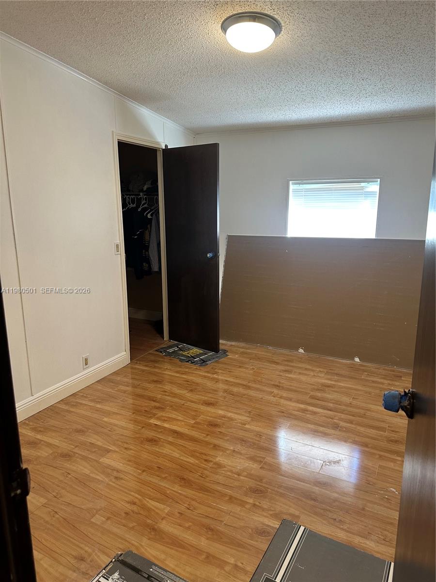 A bedroom with wood-look flooring, a closet, and an unfinished wall section under a window — 19800 SW 180th Ave Lot 266, Miami FL 33187, MIAMI, FL