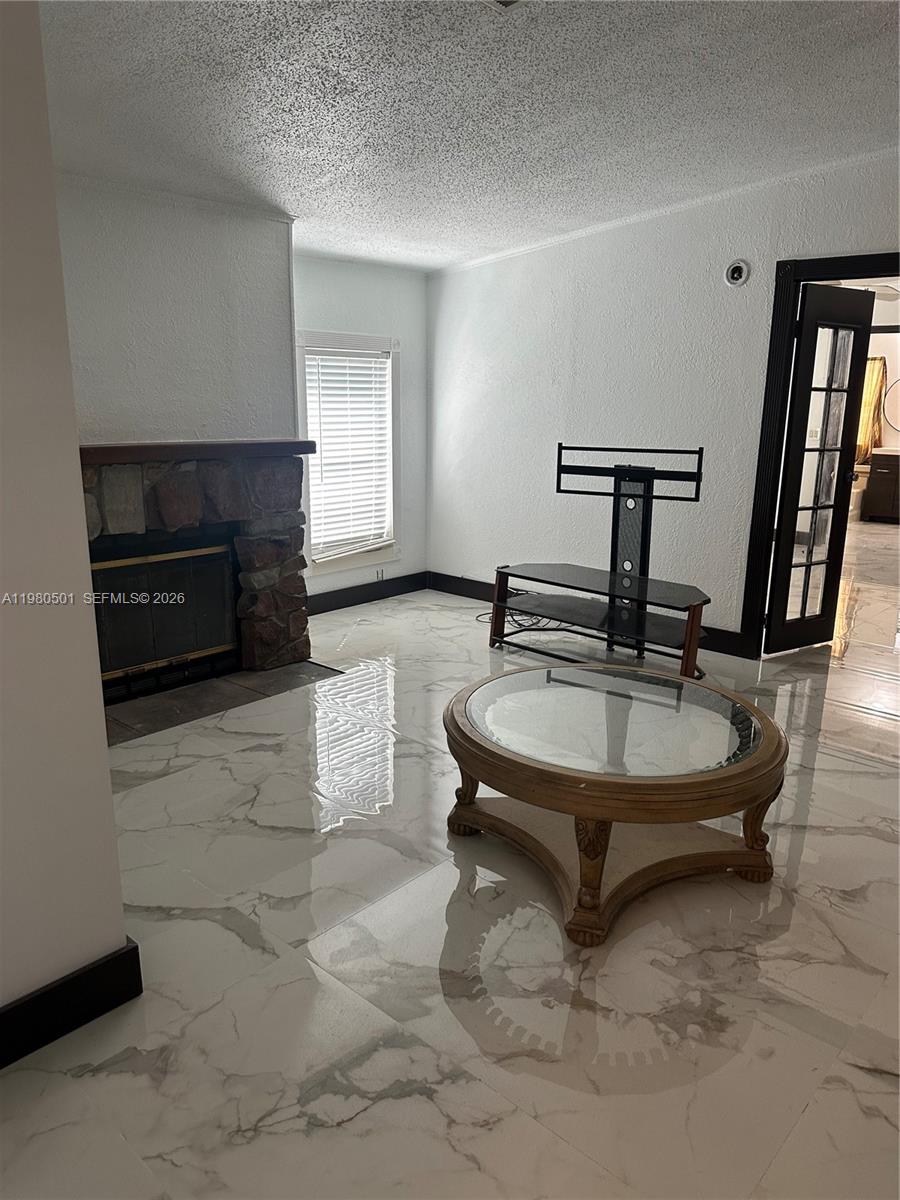 A living room features a stone fireplace, white marble-look tile flooring, and a glass coffee table — 19800 SW 180th Ave Lot 266, Miami FL 33187, MIAMI, FL