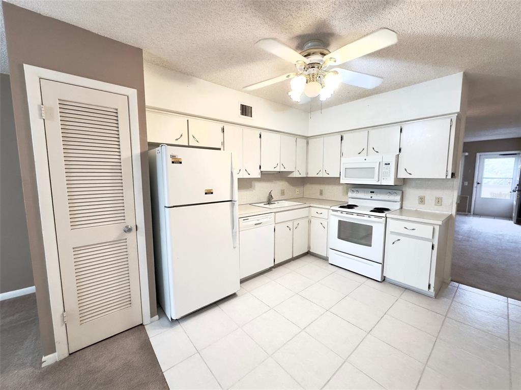 A kitchen with white cabinets, white appliances, a ceiling fan, and tiled flooring — 2287 PHILIPPINE DRIVE UNIT 29, CLEARWATER, FL