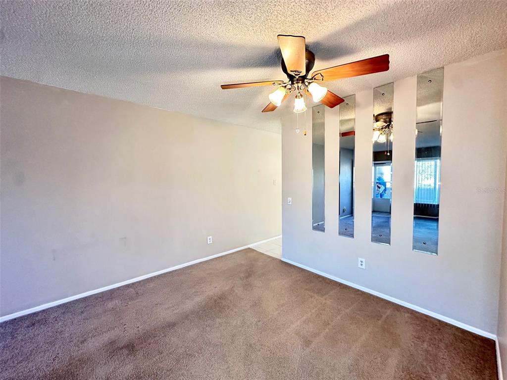 A carpeted room features a ceiling fan and vertical wall mirrors — 2287 PHILIPPINE DRIVE UNIT 29, CLEARWATER, FL