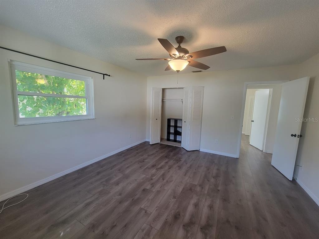 A bedroom with wood-look flooring, a ceiling fan, a closet, and a window — 6290 CONISTON TERRACE, NORTH PORT, FL