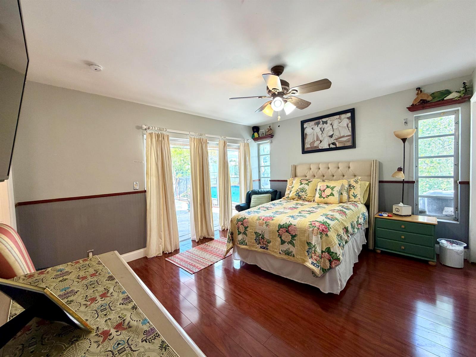 A bedroom features a floral bedspread, hardwood floors, a ceiling fan, and sliding glass doors — TAMARAC, FL