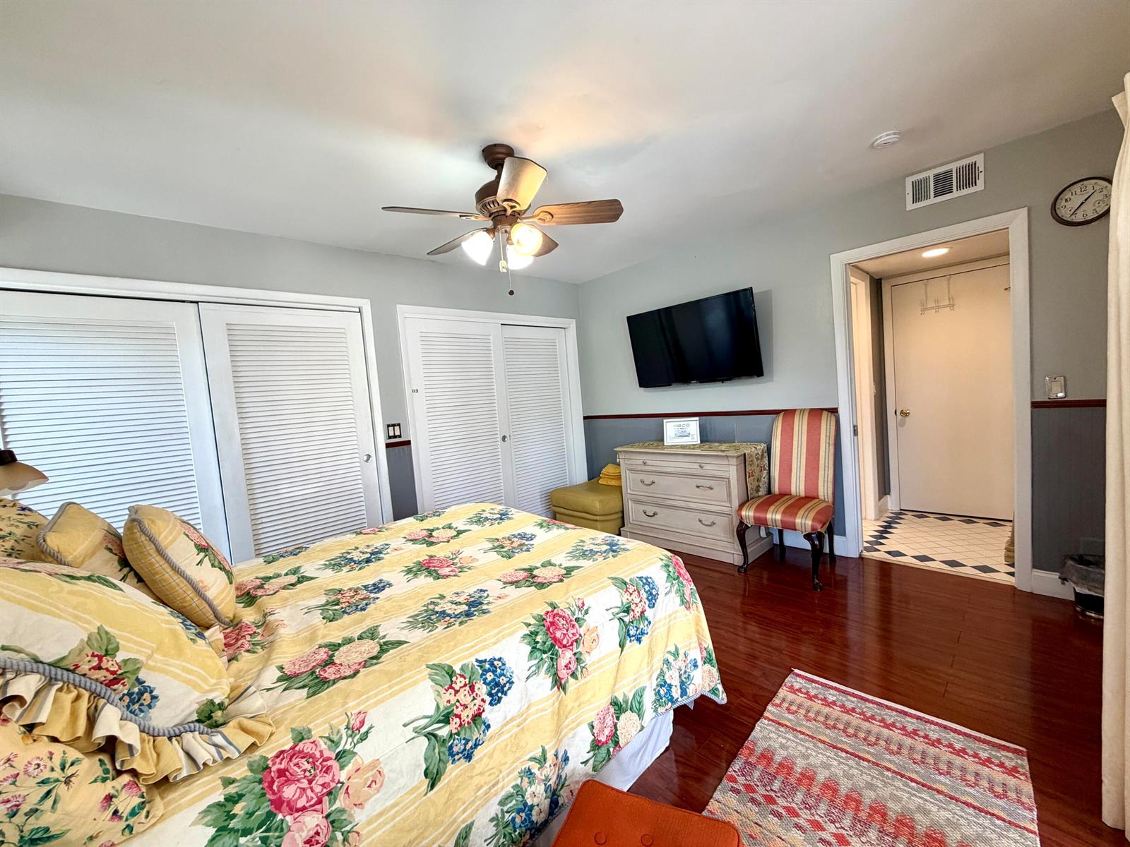 A bedroom features a floral bedspread, a ceiling fan, a wall-mounted television, and hardwood floors — TAMARAC, FL