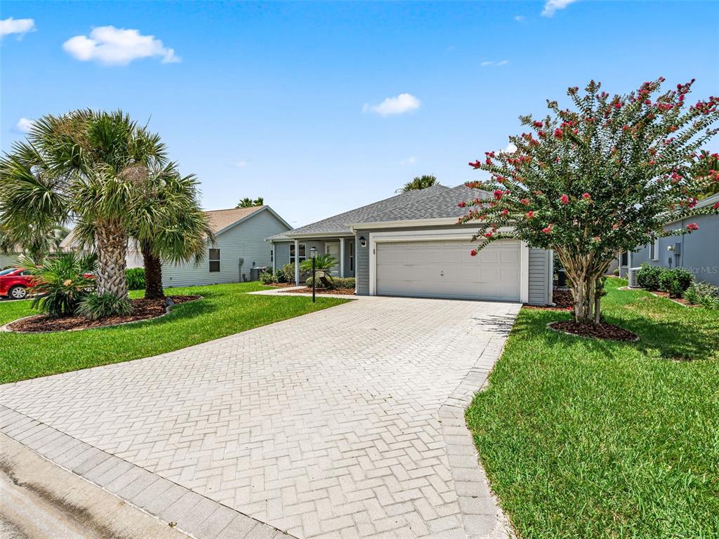 A single-story house with a paved driveway, a two-car garage, and a landscaped front yard — 1506 ROCHA LANE, THE VILLAGES, FL