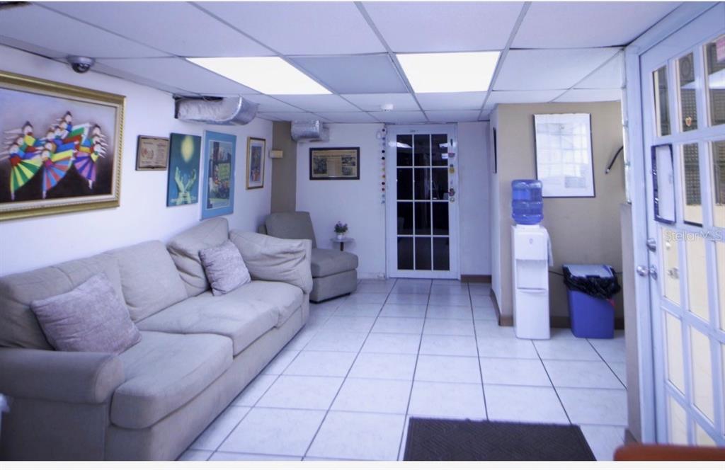 A waiting room with a beige sofa, tiled flooring, drop ceiling, and a water cooler — 20 ALBOLOTE AVE GUAYNABO IDUSTRIAL PARK, GUAYNABO, PR