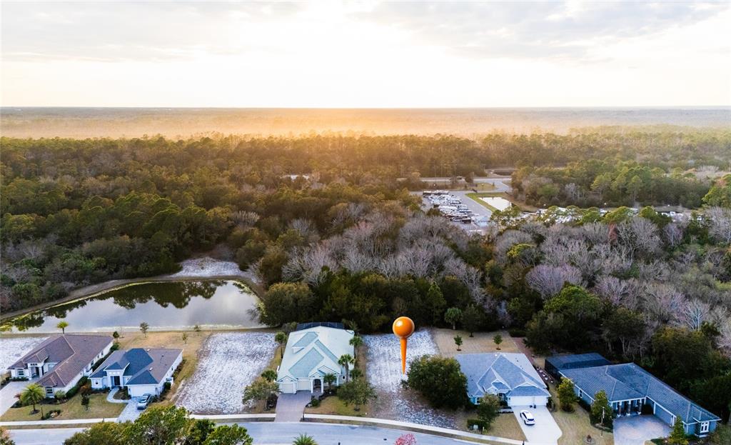 An outdoor swimming pool with lap lanes overlooks a lake at sunset — 43 N LAKEWALK DRIVE, PALM COAST, FL