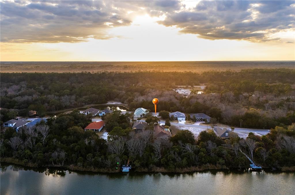 An aerial view shows a lake with a fountain at sunset next to a house — 43 N LAKEWALK DRIVE, PALM COAST, FL