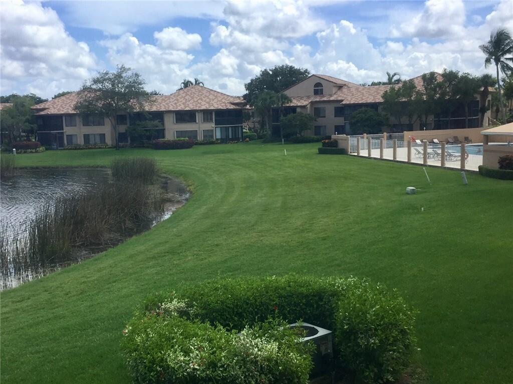A grassy lawn slopes toward a pond in front of multi-story apartment buildings — 7344 Clunie Place # 13604, Delray Beach FL 33446, DELRAY BEACH, FL