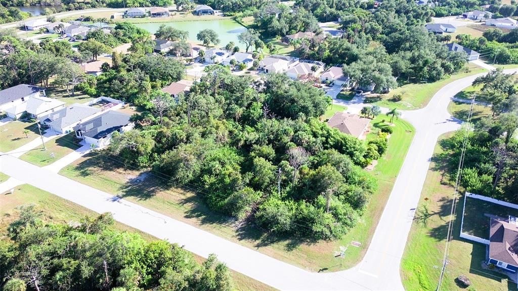 An aerial view shows a wooded vacant lot situated between two residential streets — 199 COUGAR WAY, ROTONDA WEST, FL