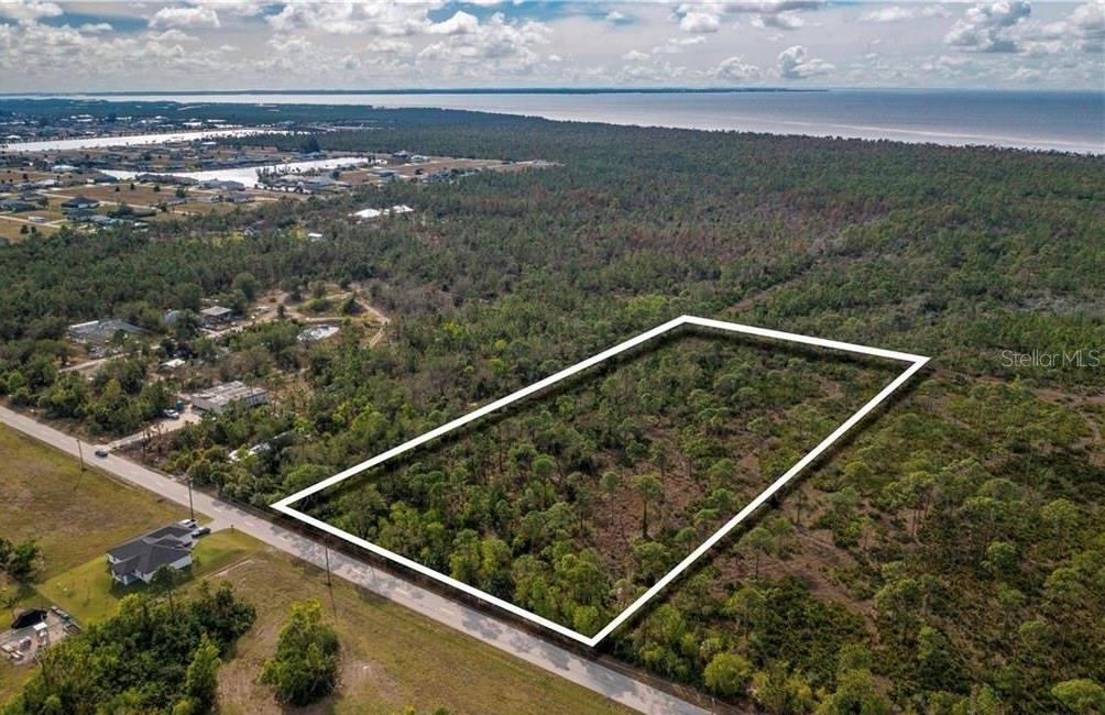 An aerial view shows a rectangular plot of land outlined in white near a coastline — 4170 OLD BURNT STORE RD, CAPE CORAL, FL