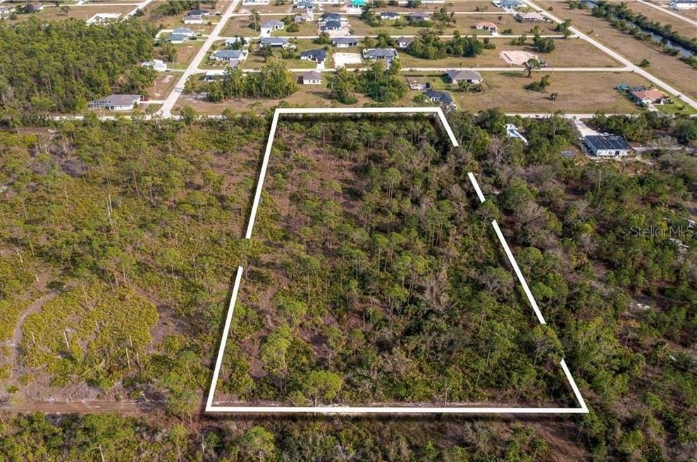 An aerial view shows a vacant, wooded rectangular lot outlined in white — 4170 OLD BURNT STORE RD, CAPE CORAL, FL