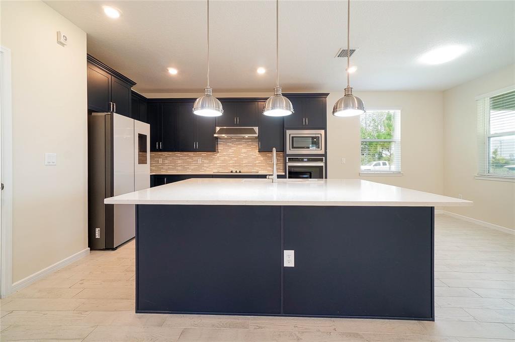 A kitchen features a large white island, dark blue cabinetry, and three hanging pendant lights — 6570 ROVER WAY, ST CLOUD, FL