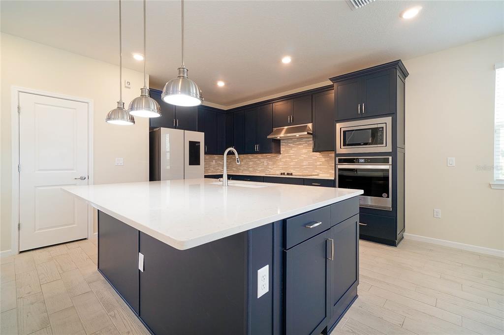 A kitchen with a large white island, dark blue cabinets, and stainless steel appliances — 6570 ROVER WAY, ST CLOUD, FL