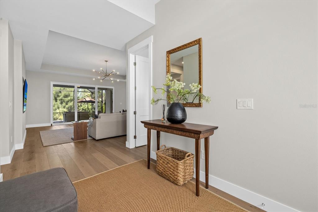 A foyer with a wooden console table, mirror, and basket leads into a bright living area — 8086 CLYDE CIRCLE, PORT CHARLOTTE, FL