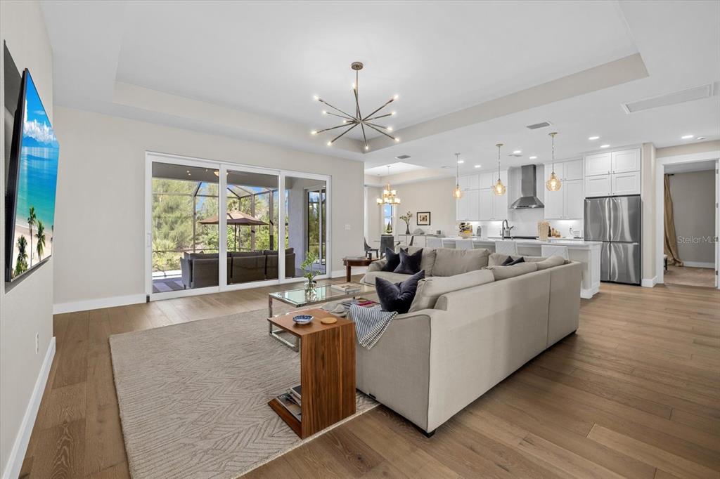A living room with light wood floors, a large sectional sofa, and an open kitchen — 8086 CLYDE CIRCLE, PORT CHARLOTTE, FL