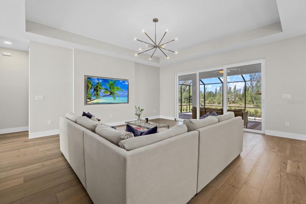 A living room features a sectional sofa, a wall-mounted television, and sliding glass doors — 8086 CLYDE CIRCLE, PORT CHARLOTTE, FL