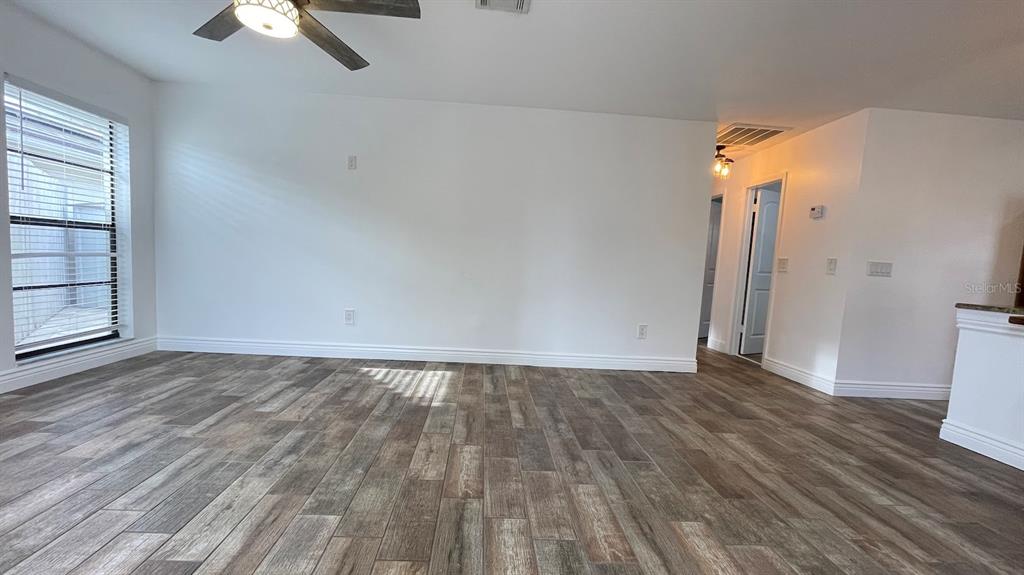 An empty room features wood-look tile flooring, white walls, a ceiling fan, and a window — 6181 SPRINGWATER STREET, ORLANDO, FL