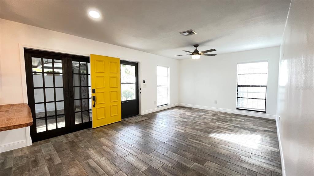 A room with wood-look tile flooring, a yellow front door, and dark French doors — 6181 SPRINGWATER STREET, ORLANDO, FL