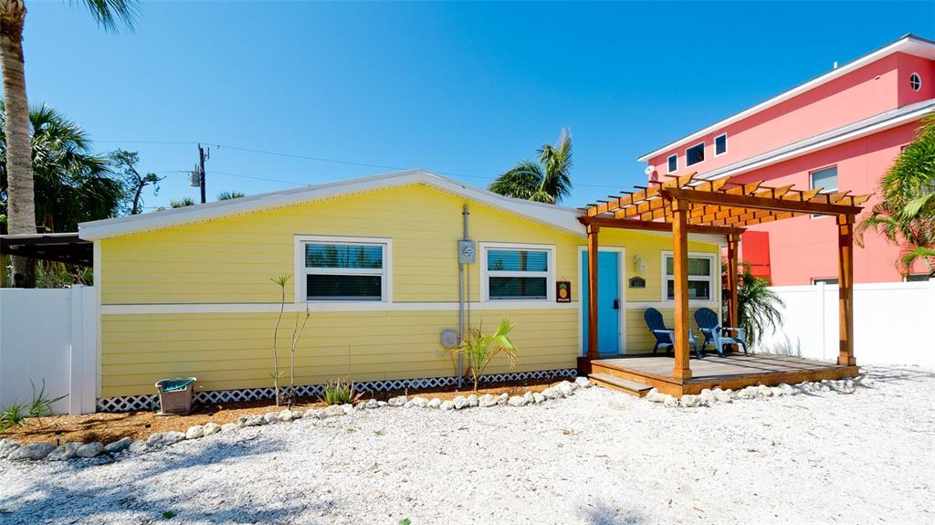 A yellow house with a wooden pergola over a front deck and gravel yard — 601 SAINT JUDES DRIVE, LONGBOAT KEY, FL