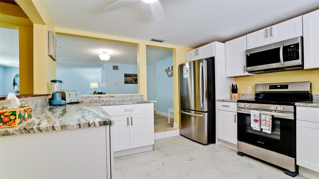 A kitchen features white cabinets, stainless steel appliances, and granite countertops — 601 SAINT JUDES DRIVE, LONGBOAT KEY, FL