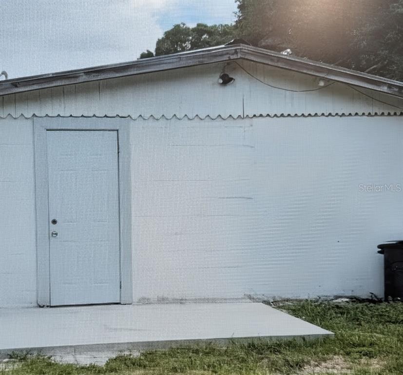 The exterior of a white building features a single door and a concrete patio — 2725 SAMPLE STREET, KISSIMMEE, FL